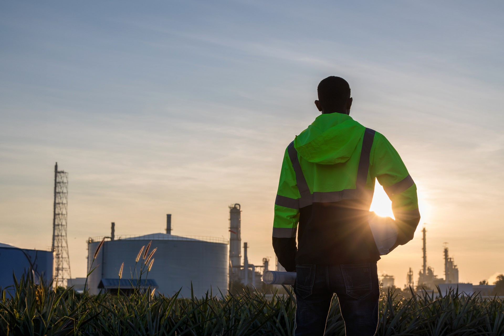 The smart civil engineer working outdoor next to the power plant. Engineer working in the industry,outdoor. Engineer manager  with white safety helmet standing front of oil refinery.